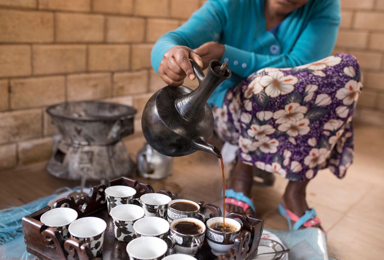 A woman pouring coffee from a jebena during an Ethiopian coffee ceremony